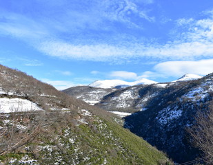 Winter landscape with snowy mountains, valley and road with blue sky. Ancares, Lugo, Galicia, Spain.