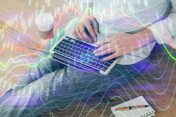 Forex graph with businessman working on computer in office on background. Concept of analysis. Double exposure.