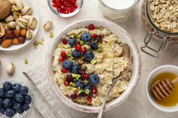 Oatmeal porridge with fresh berry, nuts and honey in bowl