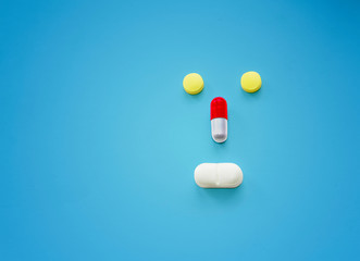Face shaped pills on blue background