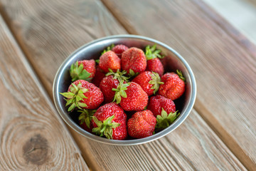 Fresh ripe strawberries in bowl on wooden table