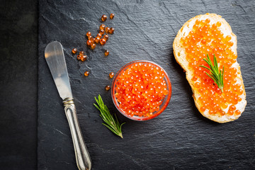 Delicious red caviar on black slate background, top view