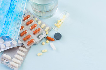 Top view of assorted medicine pills and tablets, glass of water.