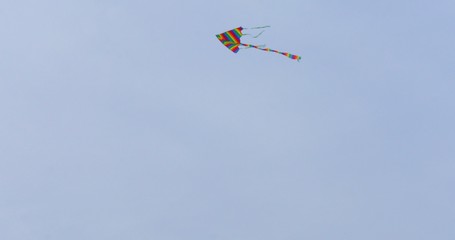 Colorful kite flying in blue sky. Toy for fun and leisure activity. Recreation.