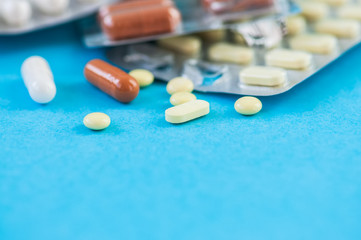 Close up of assorted medicine pills and tablets on a blue background.