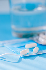 Fototapeta na wymiar Close up of medicine pills or capsules on blue medical mask on a blue background.