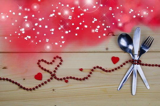 Valentine concept. Fork, knife and tablespoon tied with red pearls. Pink smoke with magic light.Invitation to the Valentine`s menu. Spoon, fork, knife, red pearls, hearts and pink smoke.