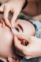 The master prepares the client for eyelash extension - A silicone pad is glued on the lower eyelid - eyelash extension procedure
