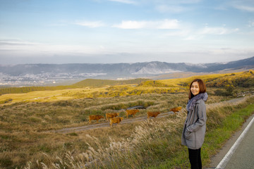 Naklejka premium Lonely girl in Area of Aso active volcano background with smoke at Mount Aso Nakadake, Kumamoto, kyushu, Japan. (Photo grain some noise on film colour)