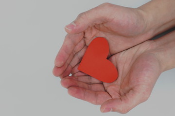 Human hands holding a red heart. Kindness, love, sharing and charity concepts