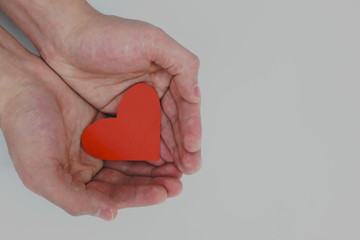 Fototapeta premium Human hands holding a red heart. Kindness, love, sharing and charity concepts
