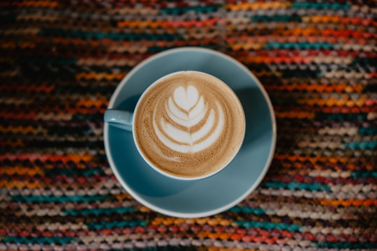 cafe con leche, latte art en taza azul y fondo de colores