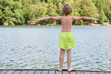 Little boy on a jetty at the bathing lake