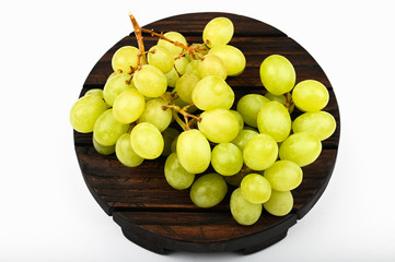 Green grapes on a round wooden plate. White background. view from above. A place to write. Juicy bunch of grapes on a wooden background.