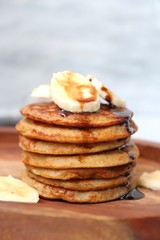 Breakfast oatmeal and banana pancakes garnished with banana slices, chocolate syrup and honey. Copy space