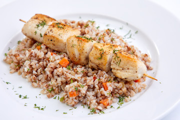 chicken kebab with buckwheat on the white plate