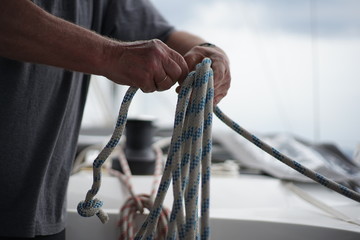 Close up of hands coiling up a rope, sheet on a sailboat