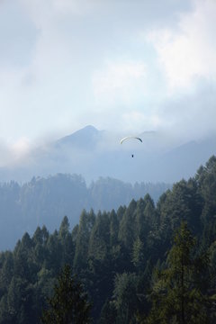 Parapendista in volo co sfondo di montagne e nuvole