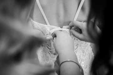 Bridesmaids assist bride to wear wedding dress