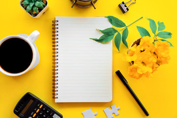 business flat lay with notepad ,pen,coffee cup on yellow background