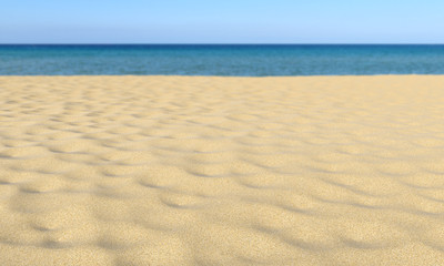 Fototapeta na wymiar Sand on sandy beach, blue sky and sea, shallow dof