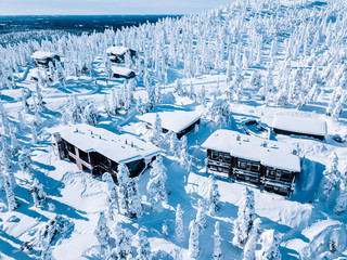 Aerial view of wooden log cabin and snow covered trees in winter Finland Lapland.