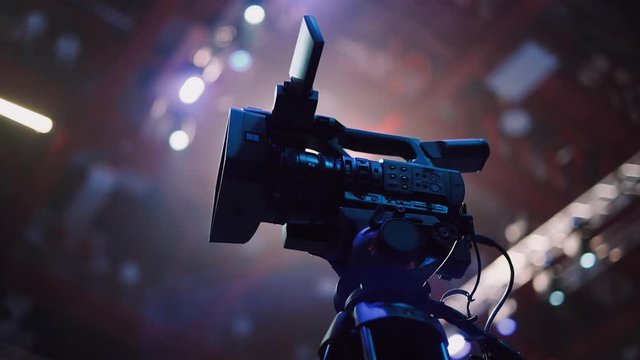 A professional video camera stands on a tripod before the start of the big event