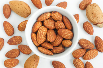 Almonds in the white ceramic bowl. Nuts close up. White background.