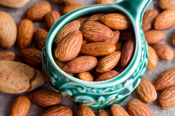 Almonds in the green bowl. Nuts close up. Dark rustic wooden background.