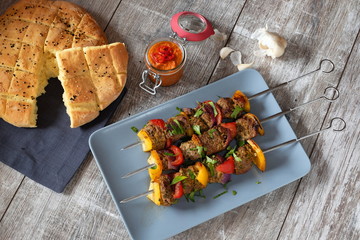 drei spieße Schisch Kebab mit Lammfleisch Paprika und Zwiebeln auf grauem teller und Holztisch...