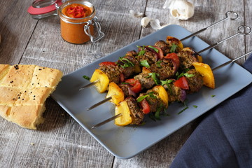 drei spieße Schisch Kebab mit Lammfleisch Paprika und Zwiebeln auf grauem teller und Holztisch...