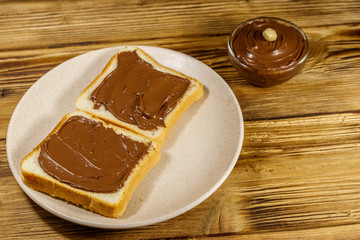 Two slices of bread with delicious chocolate hazelnut spread on wooden table