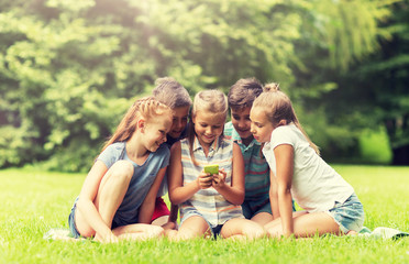 Fototapeta premium friendship, childhood, technology and people concept - group of happy kids or friends with smartphone in summer park