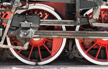 Red wheels of a steam locomotive with power parts