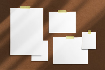 Mood-board composition template with blank photo cards, polaroid frames glued with yellow adhesive tape and on brown desk with geometric  shadow overlay.