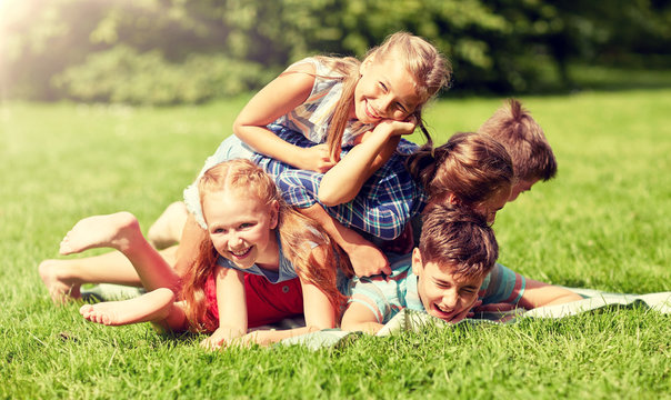 friendship, childhood, leisure and people concept - group of happy kids or friends playing and having fun in summer park