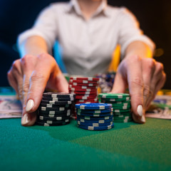 Fototapeta premium A player in a casino raises bets with chips, poker and a gaming business. The concept of a gaming business and online casino