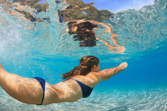 Active young woman dive, swim underwater to see tropical fishes in sea lagoon pool. Swimming activity, watersports on summer beach cruise with kid. Happy family lifestyle in adventure travel camp.
