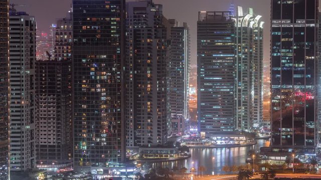 Residential and office buildings in Jumeirah lake towers district day to night transition timelapse in Dubai. Aerial panoramic view from above with modern skyscrapers