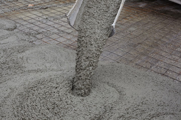 wet concrete falls from concrete bucket. Industrial construction. - 320743777