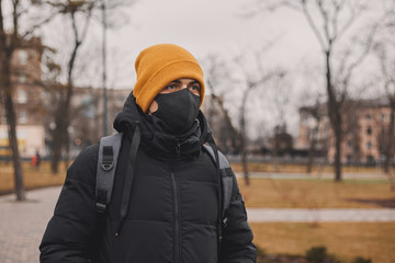 Man in orange hat and black medical mask on the street. Coronavirus is a virus that is endemic in China. Protection from the illness for children. Health safety concept.