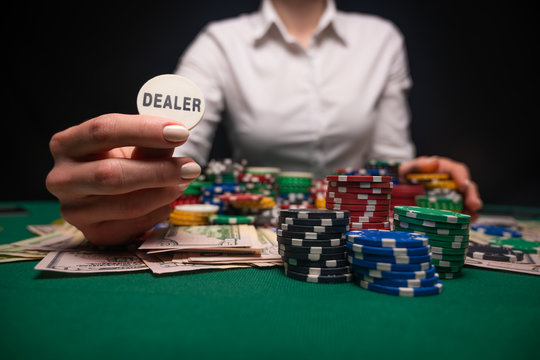 Girl dealer holding a dealer chip in a casino at the gaming table. Las Vega, gaming business. Concept of gaming business and success.