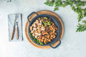 Healthy food. Pan of baking chicken meat, fried sweet potato and brussels sprouts. Top view, light gray concrete surface, flat lay..