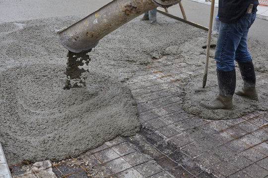 workers pouring wet concrete using concrete bucket. Industrial construction.