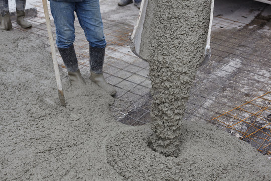 workers pouring wet concrete using concrete bucket. Industrial construction.