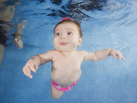 Little baby learning to swim underwater in a swimming pool