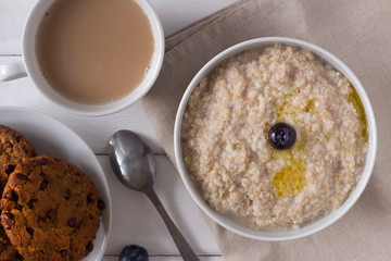 oatmeal with butter, tea and cookies on the table