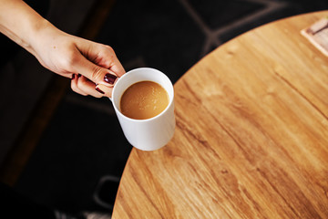 Top view of woman taking fresh morning coffee arabica from a table.