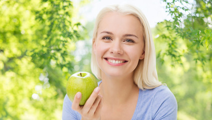 healthy eating, food, diet and people concept - happy smiling woman with green apple over natural background