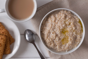 oatmeal with butter, tea and cookies on the table